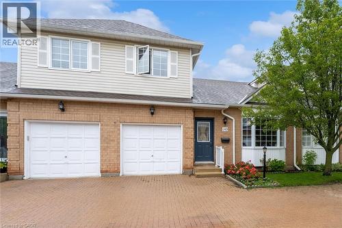 Brick and siding exterior featuring a multi-pane front door, two garage doors, and a bay window - 149 Silverbirch Boulevard, Hamilton, ON 