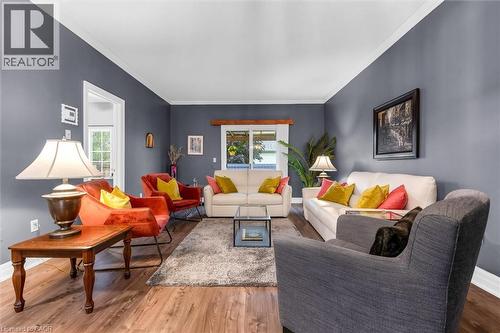 Spacious living room featuring wood-finish flooring, neutral gray walls, and white crown molding - 149 Silverbirch Boulevard, Hamilton, ON 