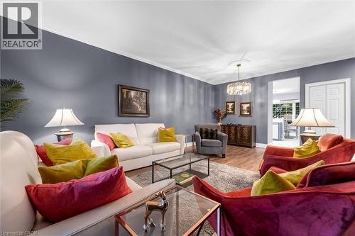 Living area featuring wood-finish flooring, a contemporary chandelier, crown molding, and a wide entryway - 149 Silverbirch Boulevard, Hamilton, ON 