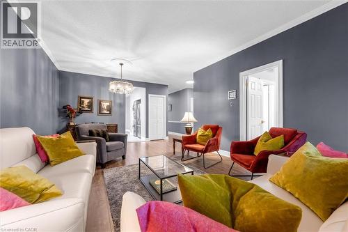 Living area featuring wood-finish flooring, crown molding, and a contemporary chandelier - 149 Silverbirch Boulevard, Hamilton, ON 