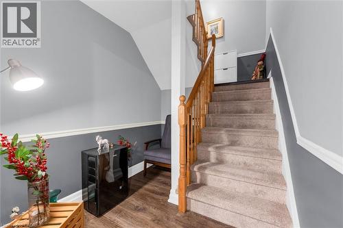 Staircase with carpeted treads and natural wood railing, complemented by two-tone painted walls with chair rail molding - 149 Silverbirch Boulevard, Hamilton, ON 