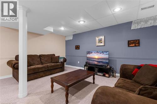 Finished basement space featuring light-colored carpet, a drop ceiling with recessed lighting, and a structural column with decorative molding - 149 Silverbirch Boulevard, Hamilton, ON 