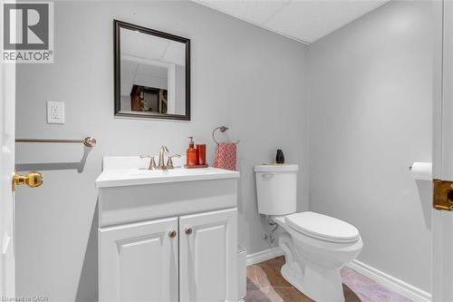 Powder room featuring a white vanity with integrated sink, brushed nickel faucet, and a wall-mounted mirror - 149 Silverbirch Boulevard, Hamilton, ON 