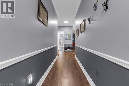 Hallway featuring wood-finish flooring, two-tone wall paint, white chair rail molding, and a flush-mount ceiling light - 149 Silverbirch Boulevard, Hamilton, ON 