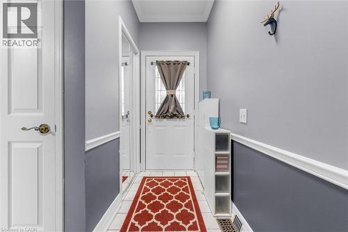 Entryway featuring a white paneled door, light gray and dark gray wall treatment, white trim work, and white tile flooring - 149 Silverbirch Boulevard, Hamilton, ON 