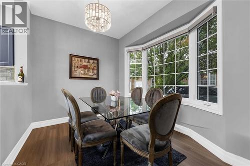 Dining area featuring a crystal chandelier, wood-finish flooring, and a multi-pane bay window - 149 Silverbirch Boulevard, Hamilton, ON 