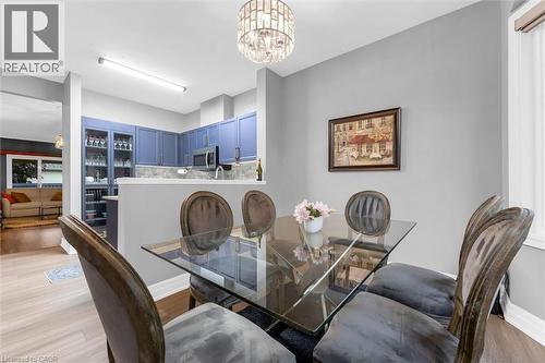 Dining area with a contemporary glass-top table, velvet upholstered chairs, and a polished chandelier - 149 Silverbirch Boulevard, Hamilton, ON 