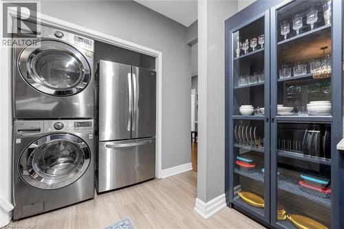 Stainless steel stacked washer and dryer appliances alongside a stainless steel refrigerator - 149 Silverbirch Boulevard, Hamilton, ON 