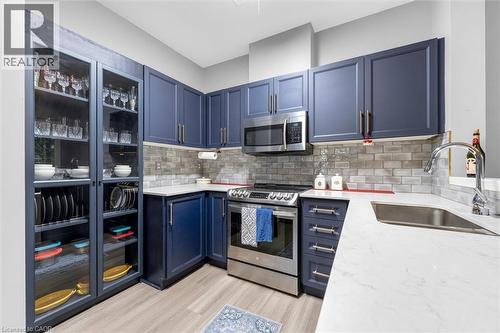Modern kitchen featuring blue shaker-style cabinetry and light wood-finish flooring - 149 Silverbirch Boulevard, Hamilton, ON 