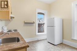 Kitchen area featuring a stainless steel sink, wood-finish cabinetry, and a white electric range with overhead ventilation - 