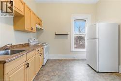 Kitchen featuring wood-finish cabinetry with black hardware, a stainless steel sink, and a white electric range with range hood - 
