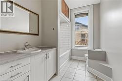 Bathroom featuring a single vanity with white cabinetry, a rectangular sink, and a gray countertop - 