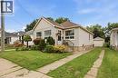 Siding exterior with a gable roofline, front porch with wrought iron railing, and a concrete driveway leading to a detached garage - 81 Vale Avenue, St. Catharines, ON 