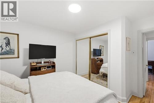 White-painted room featuring a built-in closet with mirrored sliding doors, recessed ceiling lighting, and wood-finish flooring visible through the doorway - 81 Vale Avenue, St. Catharines, ON 