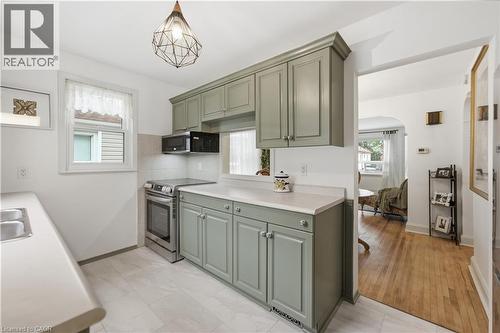 Kitchen featuring painted cabinetry, light countertops, stainless steel appliances, and a geometric pendant light fixture - 81 Vale Avenue, St. Catharines, ON 