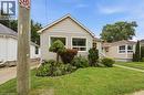 Light-toned siding exterior with multiple windows, a manicured lawn, and established front garden beds - 81 Vale Avenue, St. Catharines, ON 