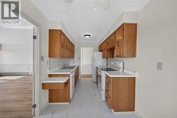 Galley kitchen featuring wood cabinetry, white countertops, white tile backsplash, and white appliances - 