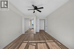 Spacious room featuring wood-finish flooring, a ceiling fan with integrated lighting, and a mirrored closet - 