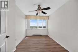 Room featuring wood-finish flooring, a ceiling fan with light fixture, and a large window - 