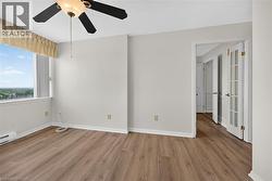Bright interior space featuring wood-finish flooring, a ceiling fan with integrated lighting, and a large window - 