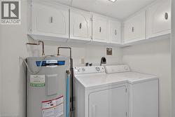 Dedicated utility space featuring overhead white cabinetry with decorative trim and metal hardware - 