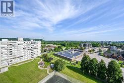 Expansive aerial perspective showcasing a multi-story building with numerous windows, a large green lawn, and a fenced court - 