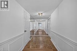 Hallway featuring wainscoting, white doors with matte black hardware, mirrored wall panels, and tile flooring - 
