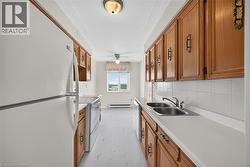 Galley kitchen featuring wood-finish cabinetry, white countertops, and a white tile backsplash - 