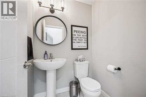 Modern bathroom featuring a pedestal sink, round wall-mounted mirror, and contemporary vanity lighting - 907 Robert Ferrie Drive, Kitchener, ON 