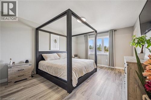 Bedroom featuring light gray walls, wood-finish flooring, two windows with vertical blinds, and a flush mount ceiling light - 907 Robert Ferrie Drive, Kitchener, ON 