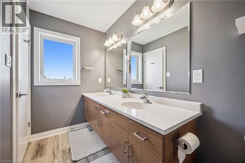 Contemporary bathroom featuring a double vanity with wood-finish cabinetry, white countertop, dual undermount sinks, and an expansive wall mirror - 907 Robert Ferrie Drive, Kitchener, ON 