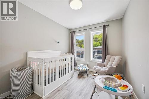 Room featuring two windows, light gray walls, wood-finish flooring, a white ceiling, and a flush-mount light fixture - 907 Robert Ferrie Drive, Kitchener, ON 