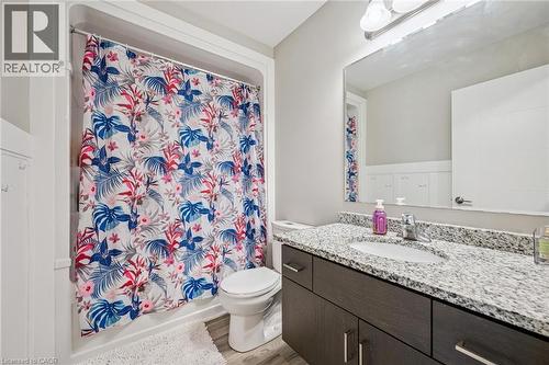 Bathroom featuring a dark wood-finish vanity with a granite countertop, undermount sink, and a large mirror - 907 Robert Ferrie Drive, Kitchener, ON 