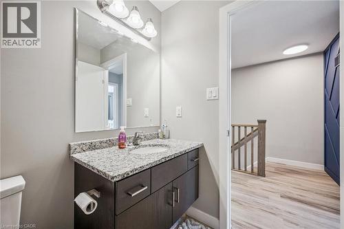 Bathroom vanity featuring a speckled countertop, undermount sink, and dark wood-finish cabinetry with silver hardware - 907 Robert Ferrie Drive, Kitchener, ON 
