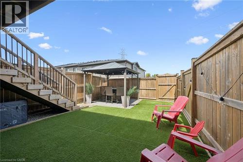 Backyard featuring artificial turf, a wood fence, and a gazebo with a paved area - 907 Robert Ferrie Drive, Kitchener, ON 