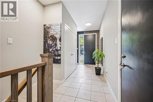 Entryway featuring light-toned tile flooring, a solid wood staircase railing, and a dark-paneled accent wall - 907 Robert Ferrie Drive, Kitchener, ON 