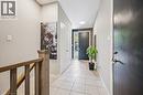 Entryway featuring light-toned tile flooring, a solid wood staircase railing, and a dark-paneled accent wall - 907 Robert Ferrie Drive, Kitchener, ON 