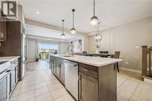 Kitchen featuring a central island with white countertop, integrated sink, and stainless steel appliances - 907 Robert Ferrie Drive, Kitchener, ON 