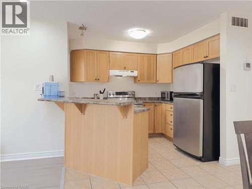 Kitchen featuring light wood cabinetry, stone-look countertops, stainless steel appliances, and tiled flooring - 78 Colton Circle, Kitchener, ON 