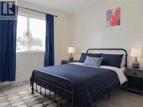 Light gray wood-finish flooring provides a neutral foundation for this room, complemented by a large window with blue drapery - 78 Colton Circle, Kitchener, ON 