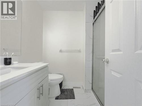 Contemporary bathroom featuring a white vanity with integrated sink and chrome pull hardware, a framed mirror, a toilet, a glass-enclosed shower with a sliding door and black hardware, and large forma - 78 Colton Circle, Kitchener, ON 