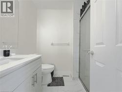 Contemporary bathroom featuring a white vanity with integrated sink and chrome pull hardware, a framed mirror, a toilet, a glass-enclosed shower with a sliding door and black hardware, and large forma - 