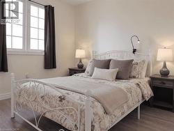 Bedroom featuring wood-finish flooring, a double window with grid panes, and neutral wall tones - 