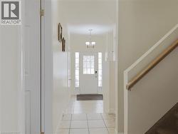 Foyer featuring tile flooring, a white paneled entry door with decorative glass inserts, and a chandelier-style light fixture - 