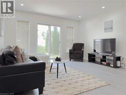 Spacious living area featuring light wood-finish flooring, recessed lighting, and a sliding glass door providing access to the outdoors - 