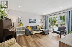 Spacious living area featuring wood-finish flooring, recessed lighting, and large windows with privacy curtains - 