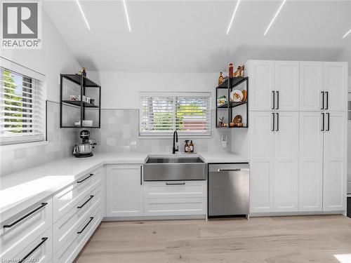 Modern kitchen featuring white shaker cabinetry with black hardware, an undermount stainless steel farmhouse sink, and light wood-finish flooring - 13 Swanhurst Boulevard, Mississauga, ON 