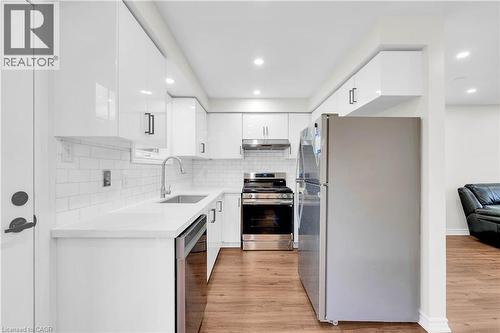 Bright kitchen featuring white cabinetry, subway tile backsplash, stainless steel appliances, and wood-finish flooring - 191 Stirling Macgregor Drive, Cambridge, ON 