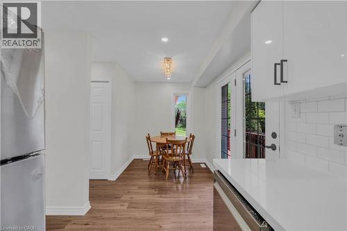 Bright kitchen and dining area featuring wood-finish flooring, white cabinetry with contemporary hardware, white subway tile backsplash, and French doors opening to an exterior space - 191 Stirling Macgregor Drive, Cambridge, ON 