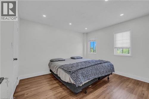Room featuring wood-finish flooring, two windows with blinds, recessed ceiling lighting, and a white interior door with black hardware - 191 Stirling Macgregor Drive, Cambridge, ON 